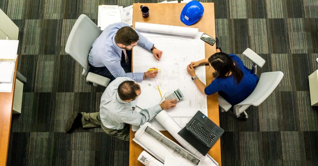 alt_text: Management w akcji: zespół omawia strategię przy biurku, planując przyszłe projekty.